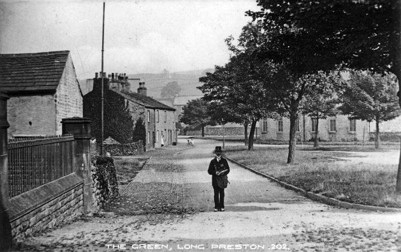 The Green 1910.JPG - View of The Green and Mr Harry Anstey, the local postman. c 1910.  The Wool Warehouse in the background opened in 1905.  ( An other postman around this period was B.Whitton ) The tall pipe on the left is a sewer vent.